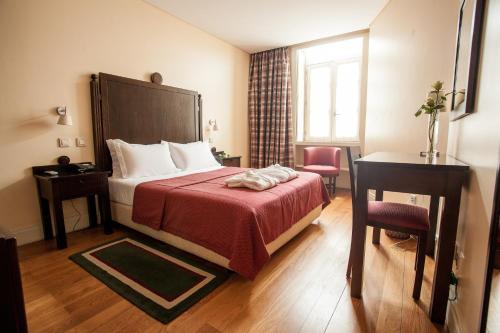 um quarto de hotel com uma cama com um cobertor vermelho em Hotel Bracara Augusta em Braga