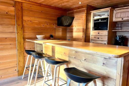 una cocina con encimera de madera y taburetes en un bar en Chic And Cosy Apt With Balcony In Megeve en Megève