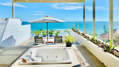 a bath tub on a patio with the ocean in the background at The Cliff Resort & Residences in Mui Ne