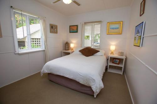 a bedroom with a white bed and two windows at 23 Bryce St Moffat Beach in Caloundra