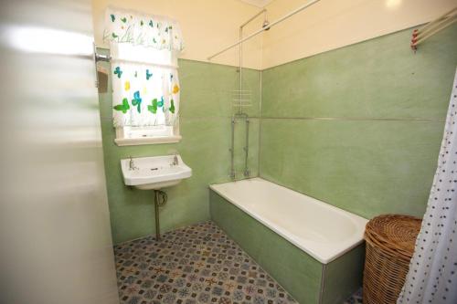 a green bathroom with a tub and a sink at 23 Bryce St Moffat Beach in Caloundra
