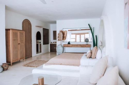 a white bedroom with a bed and a table at Hotel Sages in Canggu
