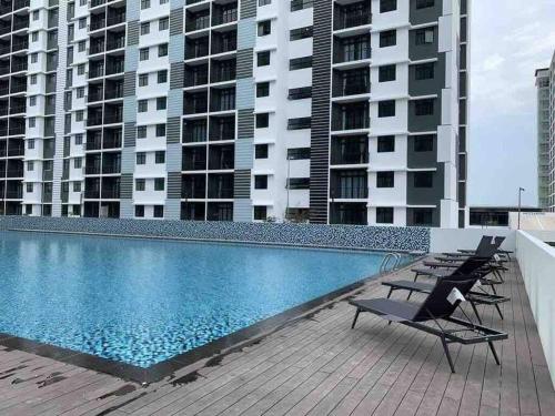 a swimming pool with chairs and some tall buildings at Urban Serviced Apartment in Bandar Penawar