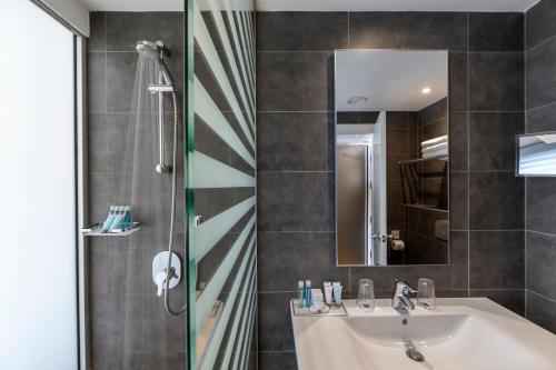 a bathroom with a sink and a shower and a mirror at Faros Hotel Ayia Napa in Ayia Napa