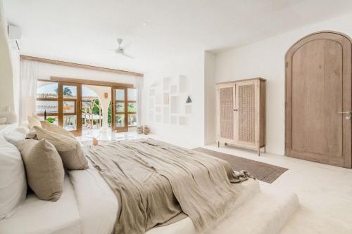 a white bedroom with a large bed and a window at Hotel Sages in Canggu