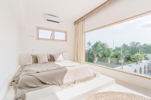a bedroom with a bed and a large window at Hotel Sages in Canggu