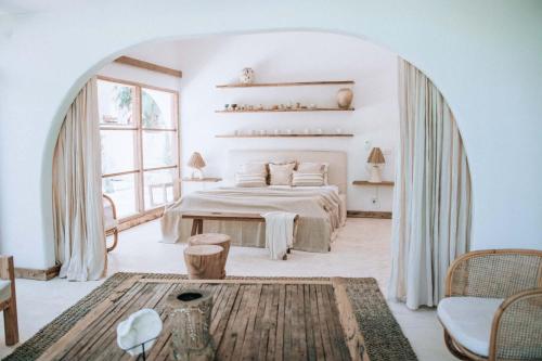a white bedroom with a bed and a large window at Hotel Sages in Canggu