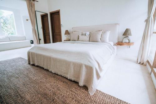 a white bedroom with a large bed and a rug at Hotel Sages in Canggu