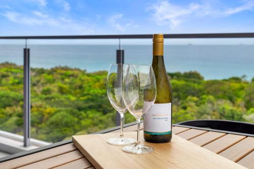 a bottle of wine and two glasses on a table at Absolute Beachfront 3 Bedroom Penthouse Bokarina Sunshine Coast in Kawana Waters