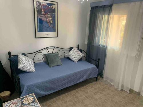 a bedroom with a blue bed and a window at Holiday house near the beach - 2 in 1 in Perítheia