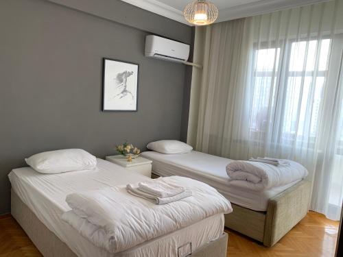 two twin beds in a room with a window at Kaplan Cosy Flat - All air conditioned & Heated 3 Bedrooms in the City in Istanbul