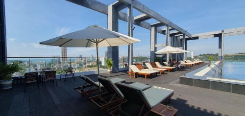 a deck with chairs and tables and an umbrella on a building at Legend Hotel and Resort in Sihanoukville