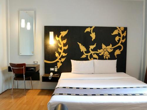 a bedroom with a bed with a black and gold headboard at Swana Bangkok Hotel in Bangkok