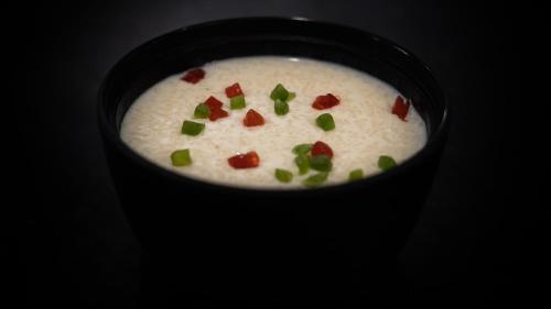 a bowl of soup with green onions on top of it at Niranjana Hotel Bodhgaya in Bodh Gaya