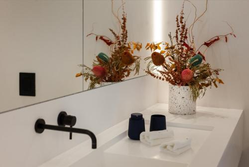 a bathroom sink with a mirror and a vase with flowers at MAP Boutique Hotel in Nicosia