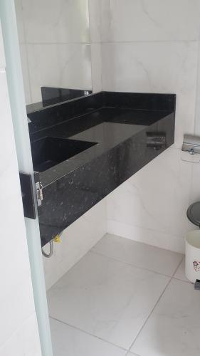 La salle de bains est pourvue d'un comptoir noir et de toilettes. dans l'établissement Sítio Alazão, à Moeda