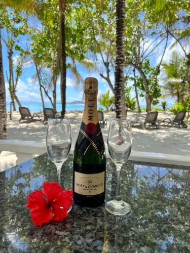 a bottle of wine and two glasses on a table at Cap Jean Marie Beach Villas in Anse Kerlan