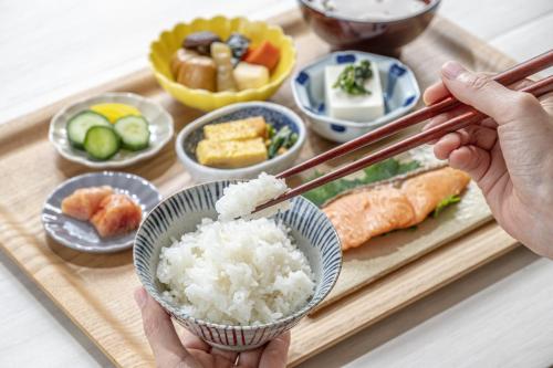 Eine Person, die Essstäbchen über ein Tablett mit Reis und Sushi hält in der Unterkunft Nasushiobara Ichimantei in Nasushiobara
