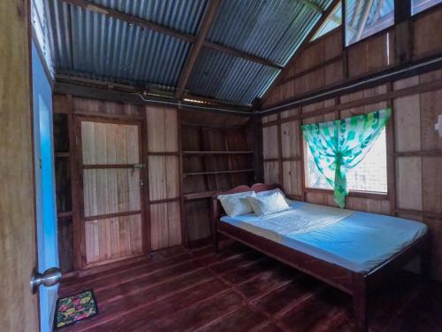 ein Schlafzimmer mit einem Bett in einem Holzzimmer in der Unterkunft Cafe Sabang Guest House in Sabang