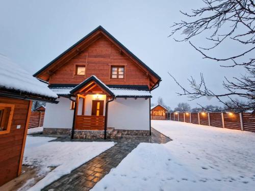 a wooden house in the snow with lights on at Holiday home Marta in nature with jacuzzi in Gospić