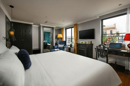 a bedroom with a large white bed and a desk at Hanoi L'Heritage Hotel & Gym - Spa in Hanoi