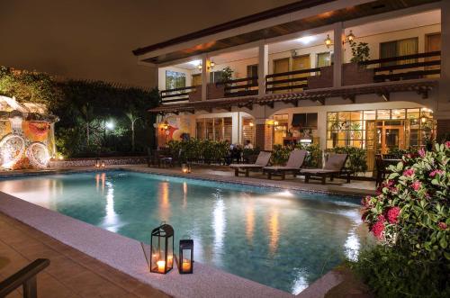 una piscina frente a una casa por la noche en La Sabana Hotel Suites Apartments en San José