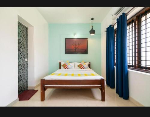 1 dormitorio con 1 cama en una habitación con cortinas azules en Tharayil Apartments, en Kochi