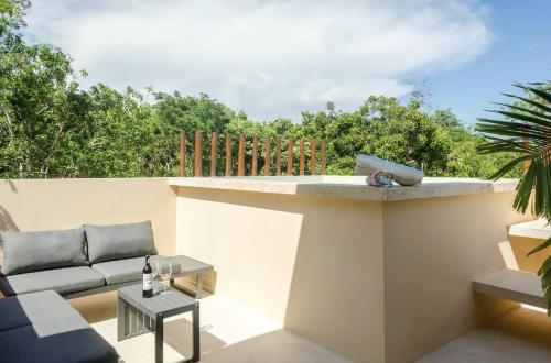 a rooftop patio with a couch and a table at Casa Kuaan Mani TH 1 in Tulum