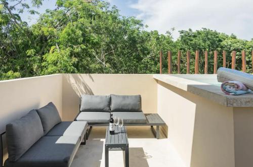 a balcony with two couches and a table at Casa Kuaan Mani TH 1 in Tulum
