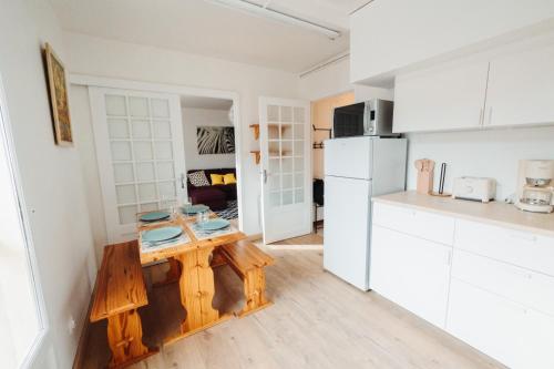 - une cuisine blanche avec une table en bois dans l'établissement L'Enfantous, à Ax-les-Thermes