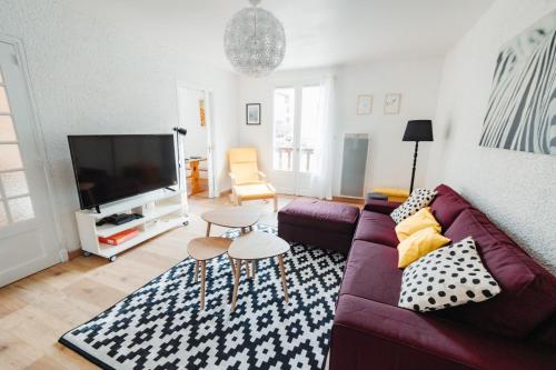 un salon avec un canapé violet et une télévision dans l'établissement L'Enfantous, à Ax-les-Thermes