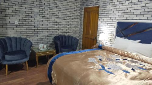 a bedroom with a bed and two chairs and a table at Royal Luxury Hotel Lahore in Lahore
