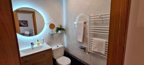 Baño blanco con lavabo y espejo en Casa deMáximo, en Navalpino