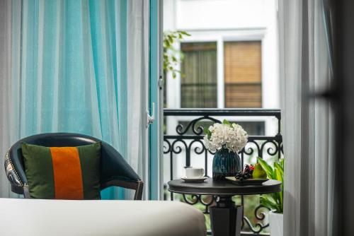 uma varanda com uma cama e uma mesa com um vaso de flores em Hanoi L'Heritage Hotel & Gym - Spa em Hanói
