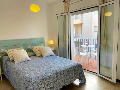 a bedroom with a bed and a balcony with a table at Apartamentos Aquarium in Roses