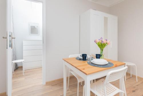 biała jadalnia z drewnianym stołem i krzesłami w obiekcie Apartment Beachy Dream by Renters w Gdańsku