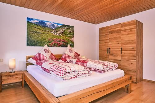 1 dormitorio con 1 cama con almohadas rojas y blancas en Chiemgauferienwohnungen - Wanderlust und Alpenrose, en Unterwossen