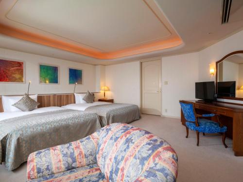 a hotel room with two beds and a desk at Hotel New Akao in Atami