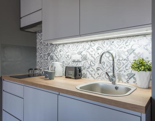 a kitchen counter with a sink and a wallpaper at Okecie Airport Studio Bakalarska 2 P&O Serviced Apartments in Warsaw