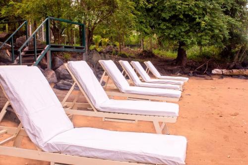 a row of white lounge chairs on a beach at Ocean View Guesthouse in São Tomé