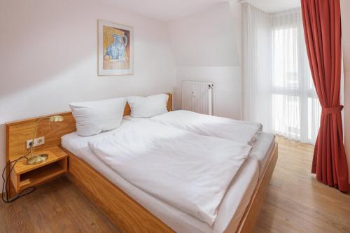 Schlafzimmer mit einem Bett mit weißer Bettwäsche und einem Fenster in der Unterkunft Die Kogge - Wohnung 9 in Norderney