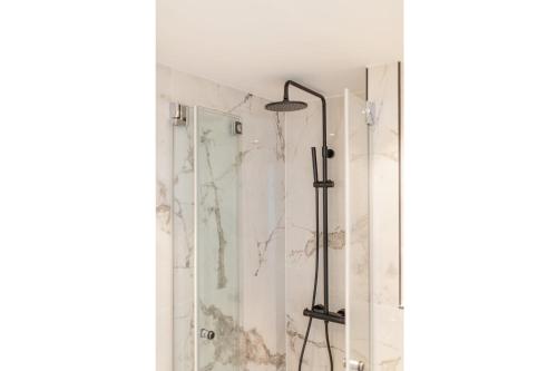 La salle de bains est pourvue d'une douche avec une porte en verre. dans l'établissement Luisensuite, à Norderney
