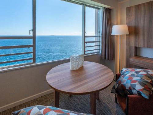 a hotel room with a table and a large window at Hotel New Akao in Atami