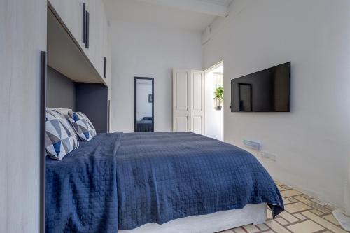 a bedroom with a blue bed and a tv at Idyllic Apartment close to Valletta in Il-Furjana