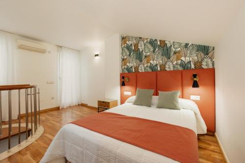 a bedroom with a large bed with an orange headboard at Apartamentos Debambú in Málaga