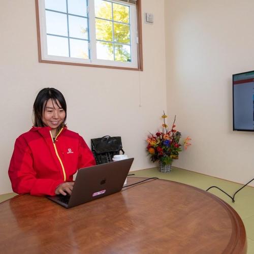 a woman sitting at a table with a laptop computer at 赤だすき_別邸 in Hakuba