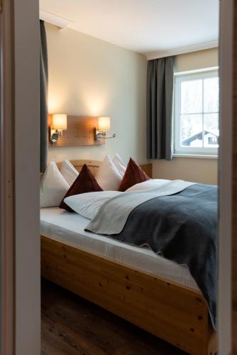 a bedroom with a bed with pillows and a window at Hotel Jagdhof in Filzmoos
