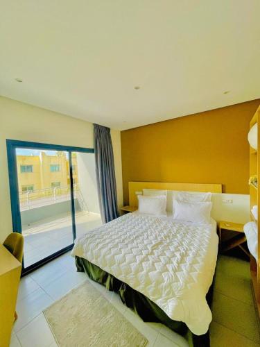 a bedroom with a large white bed with a window at Appart Hôtel Pyramides El Jadida in El Jadida