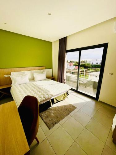 a bedroom with a bed and a green wall at Appart Hôtel Pyramides El Jadida in El Jadida