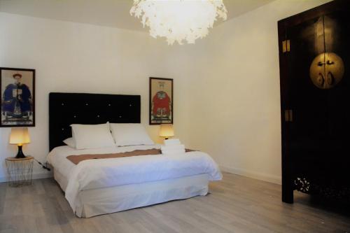 a bedroom with a large white bed and a chandelier at Chez Monsieur le directeur de la poste in Piégut-Pluviers